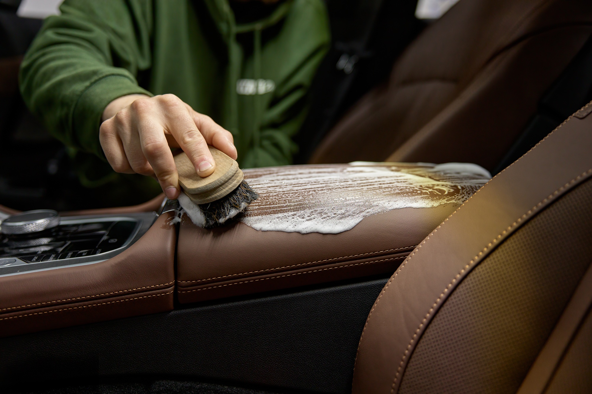 Closeup leather car interior cleaning with foam detergent and brush